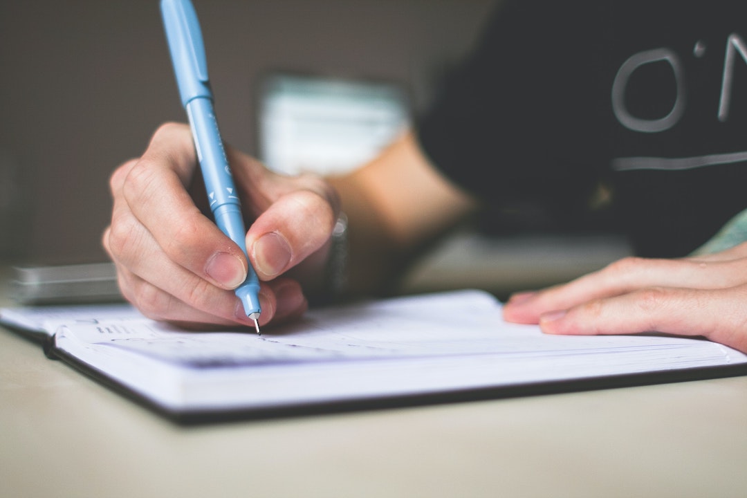 Una mano che scrive su una lista - Foto di picjumbo.com su Pexels