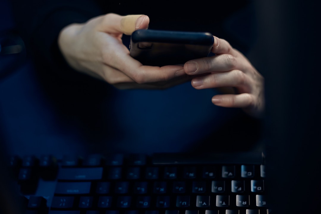 Modalità scura - Foto di una persona con un telefono nero e una tastiera nera