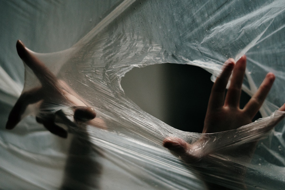 Trappole antispam - foto di mani che spuntano da un foro in un foglio di plastica trasparente