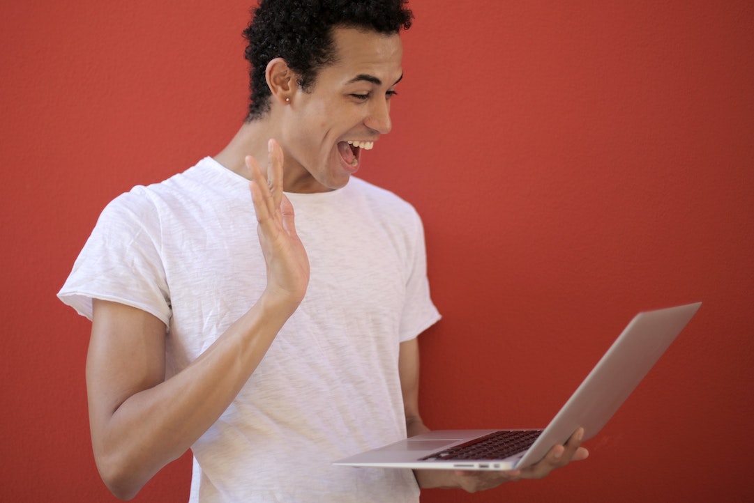 Un uomo che sorride davanti al computer, felice di vedere la sua e-mail personalizzata - Foto di Andrea Piacquadio - Pixels