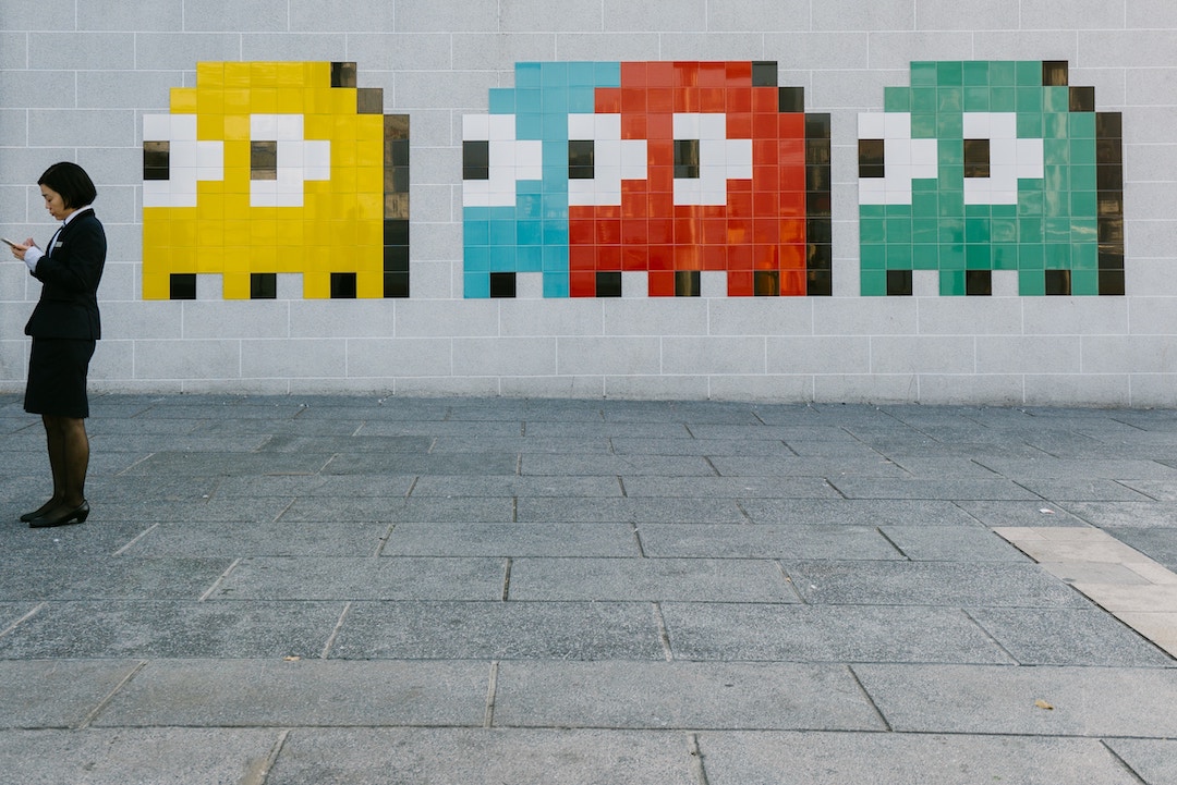Pacman che osserva una donna su un muro - Foto di Bady Abbas - Unsplash