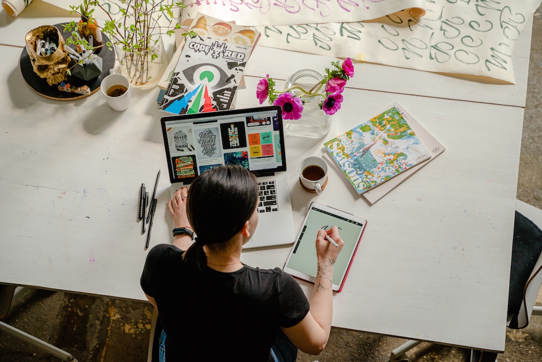 Donna davanti a un tavolo con materiale artistico e un computer. Foto di Antoni Shkraba - Pexels