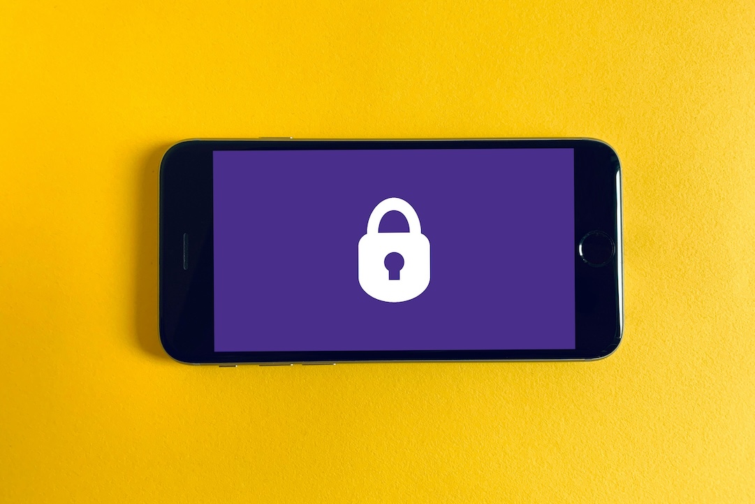 iPhone nero su sfondo giallo con un lucchetto. Foto di Franck su Unsplash